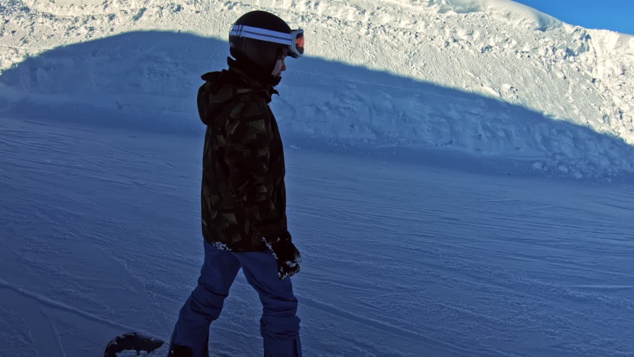 A teenage boy on a snowboard sliding by slowly