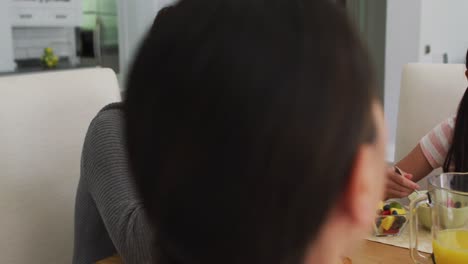 부 ⁇ 에서 행복한 아시아 부모가 아침 식사를 하고 웃는 딸과 이야기하고 있습니다.