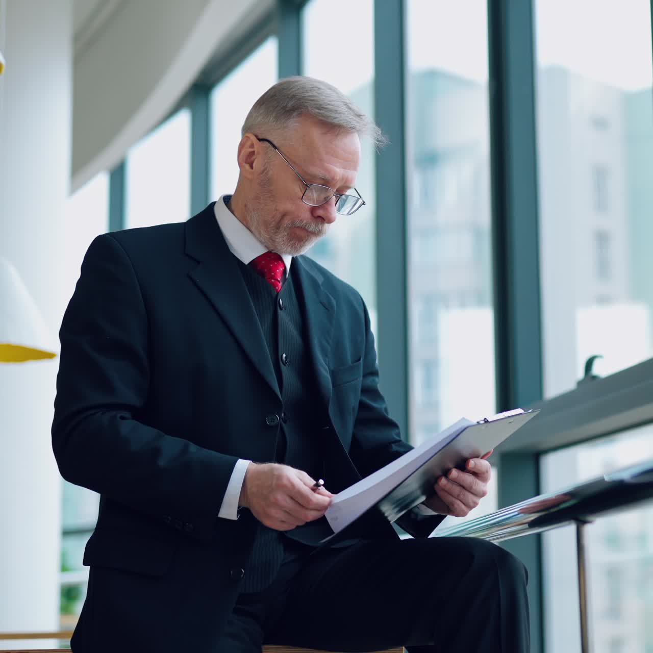Businessman is working with documents in the office throwing away papers. Video with a senior man near window.