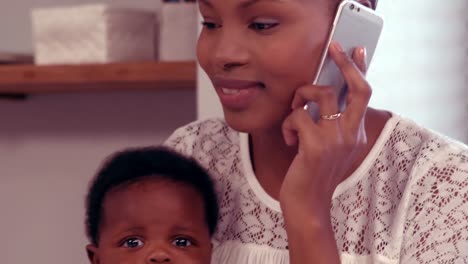 Mujer-Hablando-Por-Teléfono-Sosteniendo-A-Un-Bebé