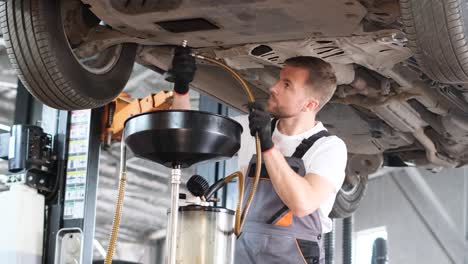 auto mechanic performing car oil change and fluid extraction