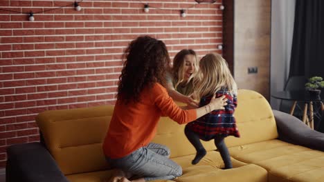 Mother-and-her-sister-are-tickling-each-other,-playing-with-small-girl