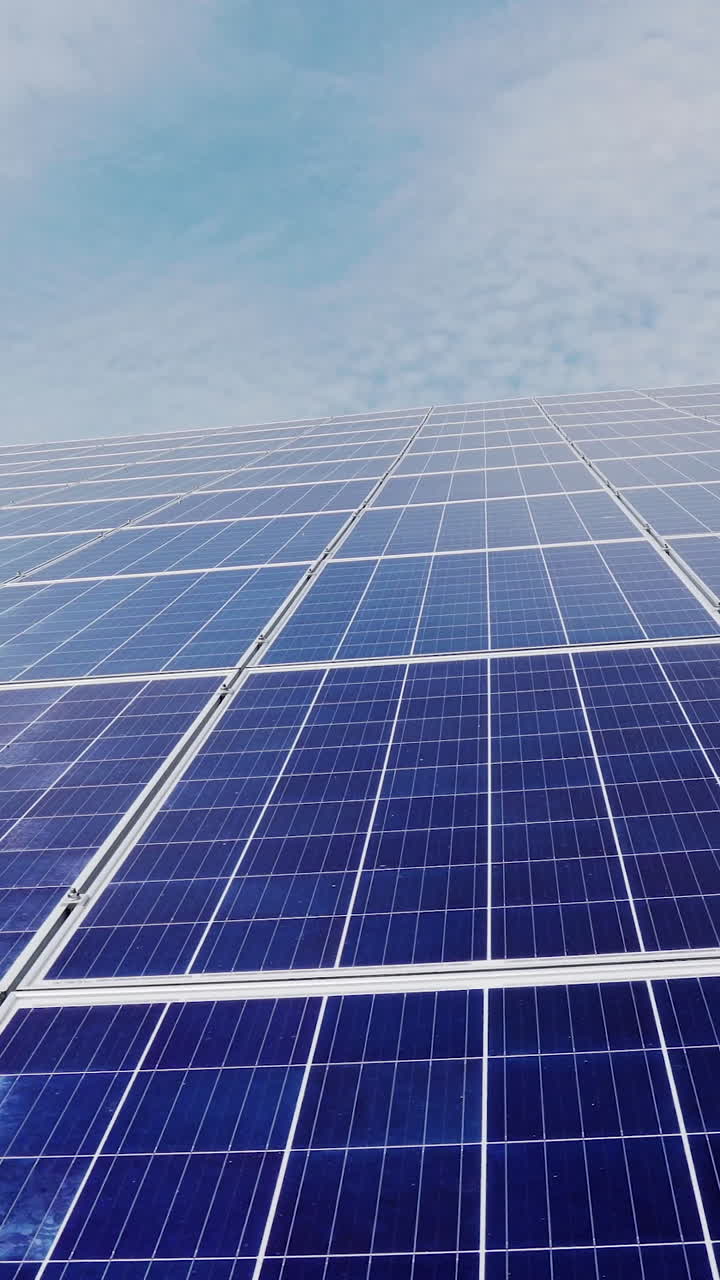 Solar farm from a large number of panels on a background of blue sky with clouds. Green energy. Vertical video