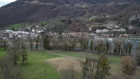 Leafless-trees-line-river-banks-in-Walensee-Switzerland-in-walking-path-across-park