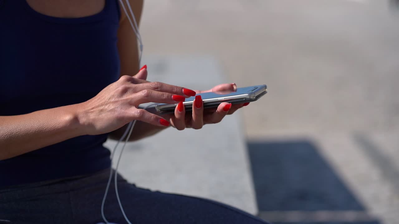 mujer joven con auriculares usando un teléfono inteligente al aire libre