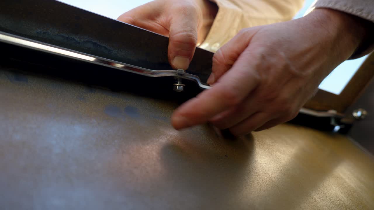 Primo piano di mani che stringono un bullone di metallo, che mostra precisione, maestria artigianale e lavoro