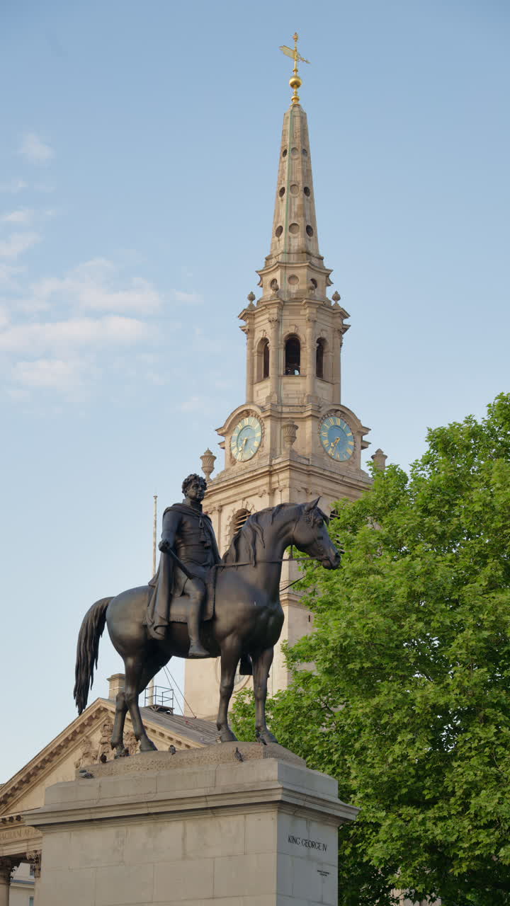 Iconic equestrian statue of King George IV with a church clock tower in the background during a bright day. Vertical, London
