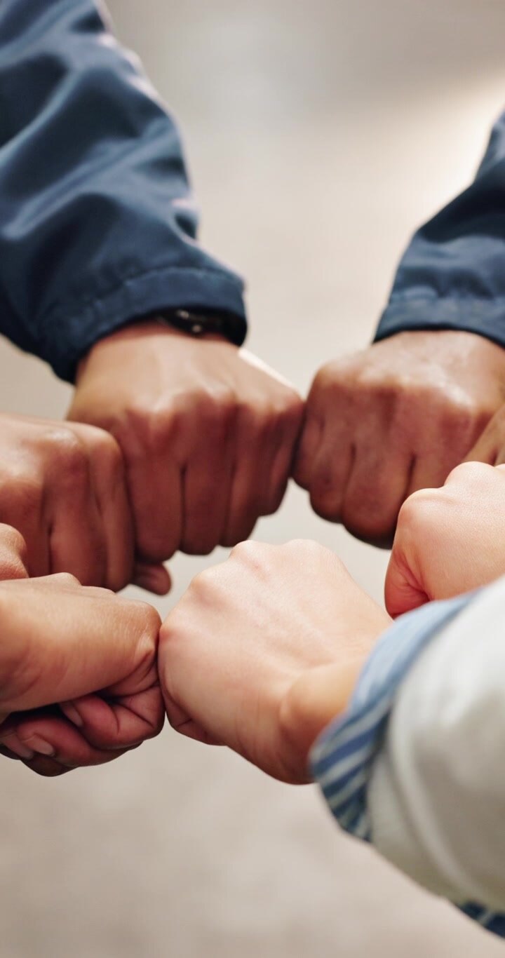Gruppo eterogeneo di persone che uniscono i pugni in un gesto di squadra