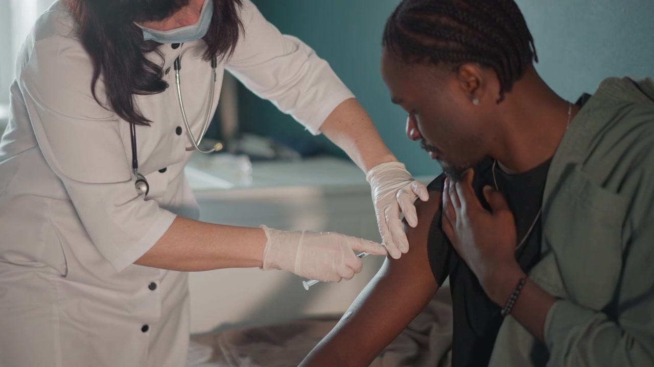 Comforting medical assistance at home. Patient receives vaccine from caring nurse in familiar surroundings. Trusting moment as nurse administers injection in supportive home environment