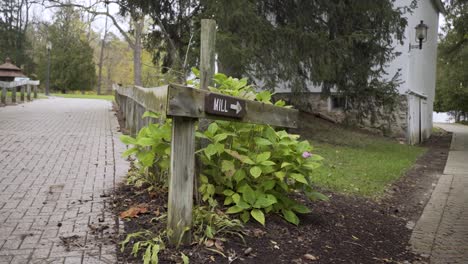 Push-in-shot-showing-a-sign-directing-visitors-to-a-grist-mill-at-Wolcott-Mill-Metropark-in-Michigan