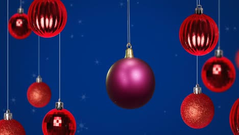 Animation-of-shiny-purple-christmas-bauble-hanging-with-red-baubles-on-blue-background-with-snow