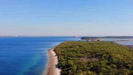 Drone-shot-rising-in-Troia,-filming-an-anchored-ship-in-the-bay