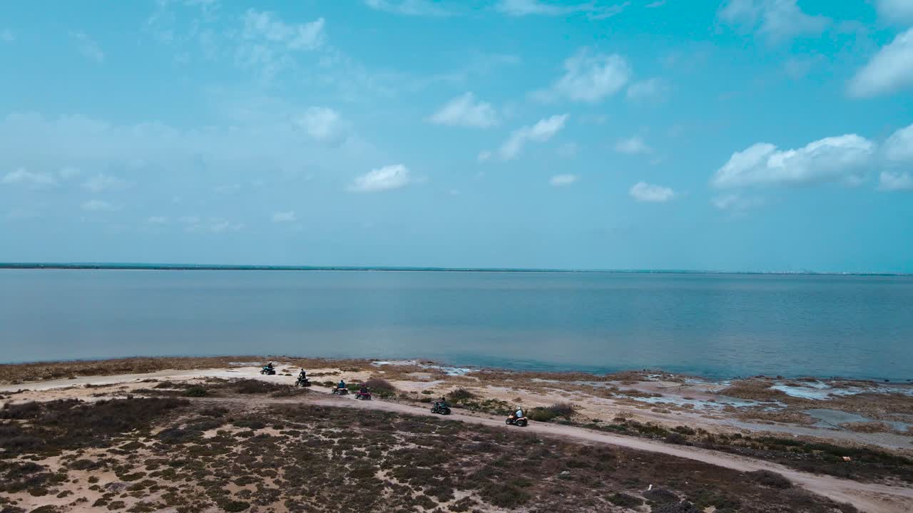 Group Riding ATVs Along a Lake Shore