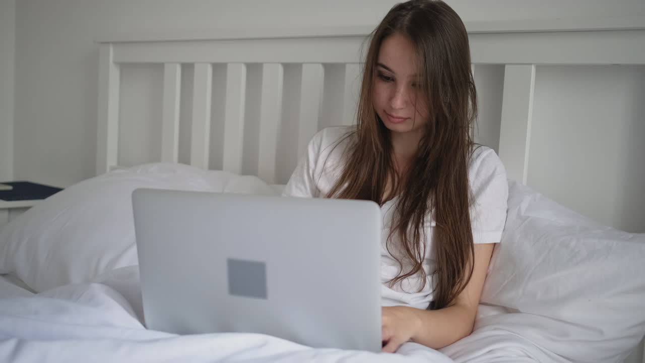 침대에 노트북으로 일하는 여자