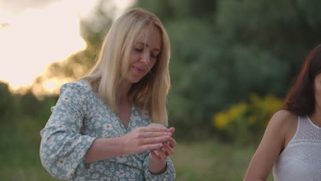 a group of young women are sculpting from clay in nature in a park in an open space. the girl is engaged in close-up sculpting smiles enjoys the process.