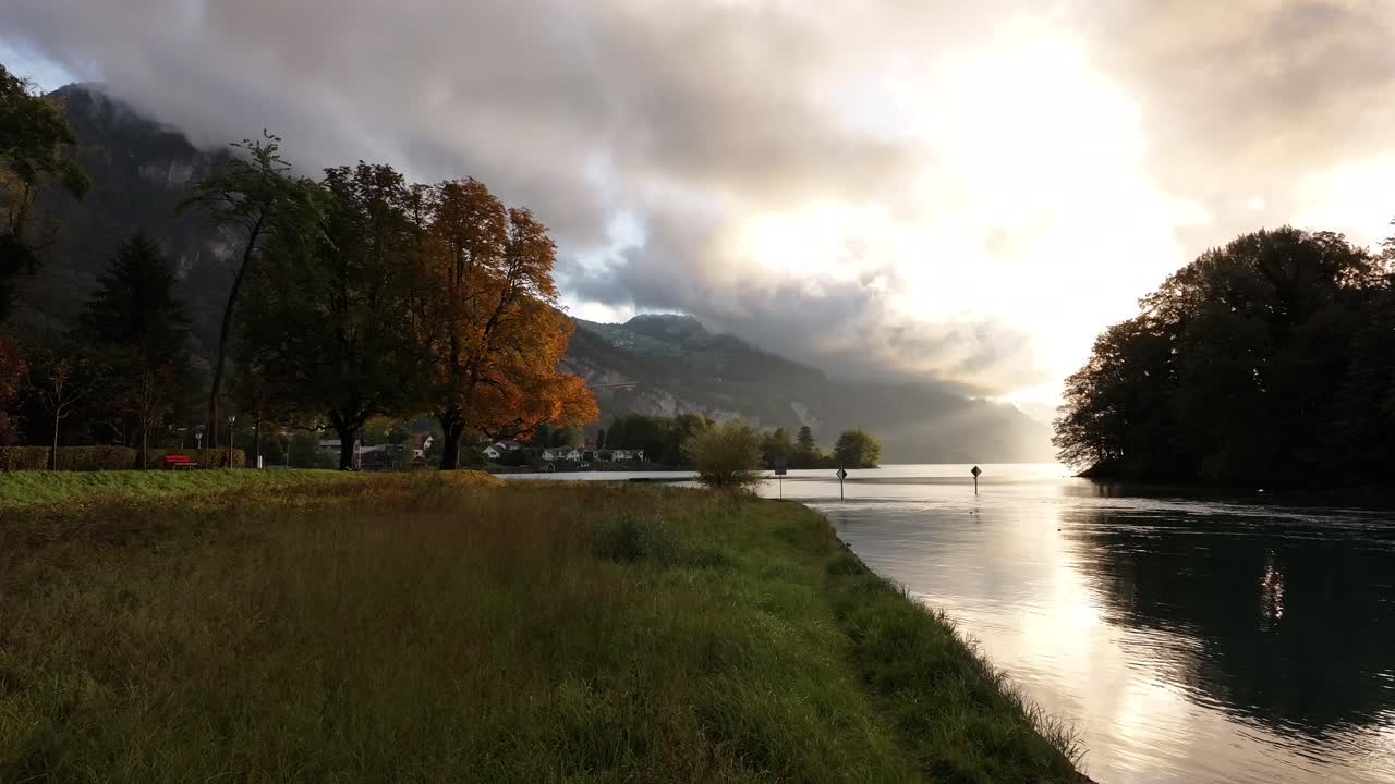 A peaceful and tranquil scene of Lake Walensee, Switzerland, enveloped in autumn mist and clouds. The calm waters and scenic surroundings create a serene atmosphere.