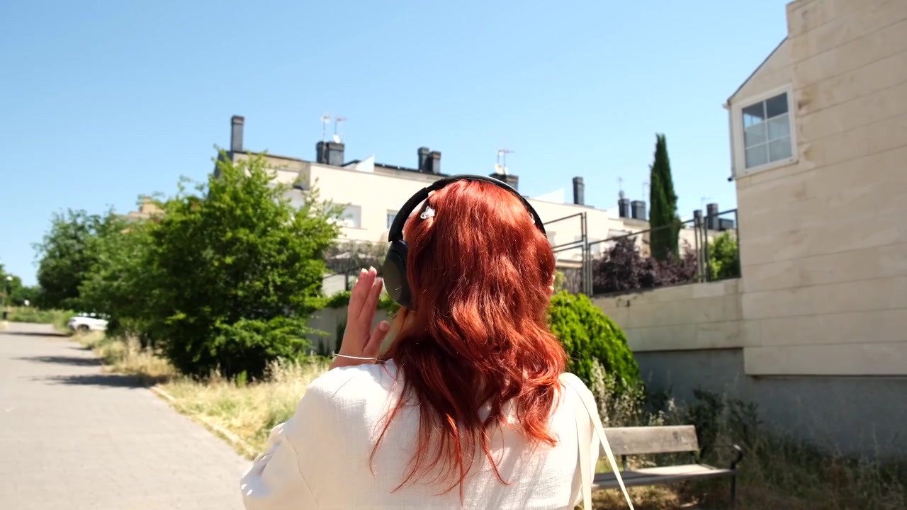 Giovane donna con i capelli rossi che ascolta musica all'aperto