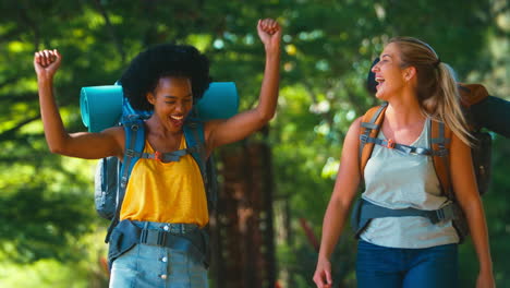 two female friends with backpacks setting off on vacation hiking through countryside together