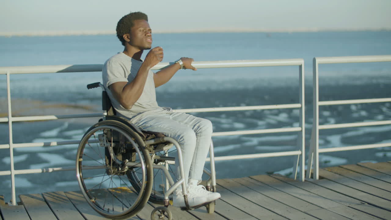 joven en silla de ruedas disfrutando de un espresso para llevar en el paseo marítimo