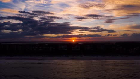 Hyperlapse-Bei-Sonnenuntergang-Aus-Der-Luft-An-Einem-Ozeanstrand-Mit-Dramatischen-Wolken