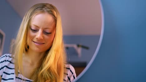 a young woman engaged in introspection and creativity while gazing into a mirror, showcasing her natural beauty and soft lighting in a calm room environment