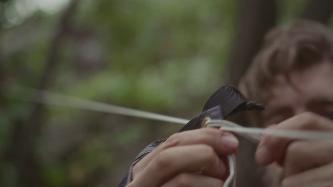 Close Up of Man Securing Tent Cord during Camping Setup