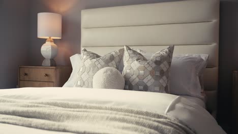 push-in-shot-of-a-neatly-made-bed-with-white-decor-and-the-sunlight-shining-in-through-a-window