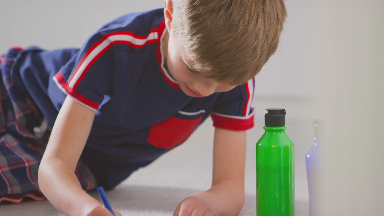 침실 에 있는 소년 이 생일 이나 어머니 의 날 을 축하 하기 위해 카드 를 만드는 것