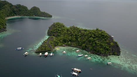 Aerial-View-Of-Boats-With-Tourists-Floating-On-Calm-Blue-Sea-In-Coron-Island,-Palawan,-Philippines
