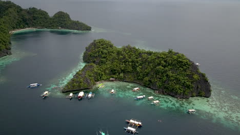 aerial view of boats with tourists floating on calm blue sea in coron island, palawan, philippines