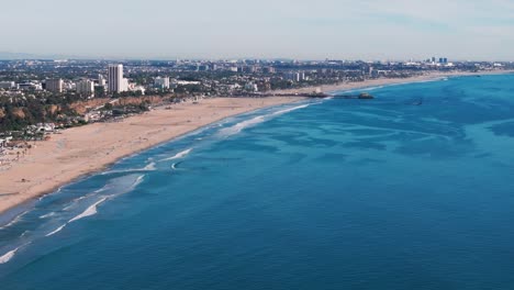 drone disparado volando a la izquierda alto sobre la playa de santa mónica y el muelle en la