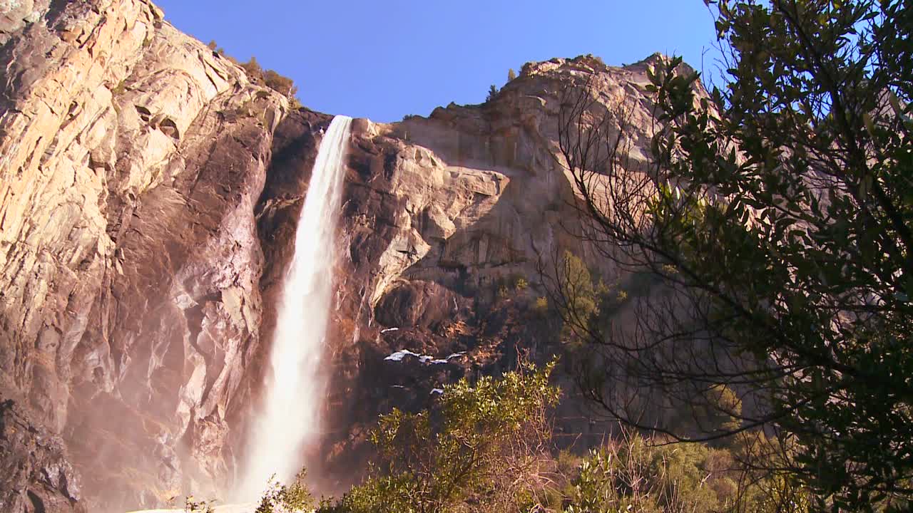 paneo de ángulo bajo a través de una hermosa cascada en el parque nacional de yosemite mientras arroja un arco iris 1
