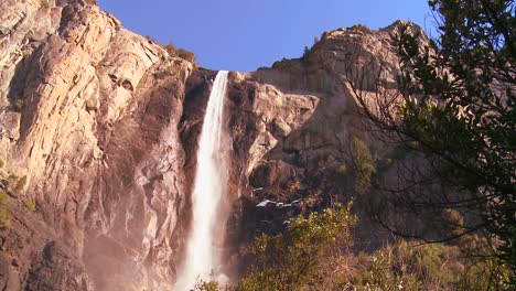 Low-angle-pan-across-a-beautiful-waterfall-in-Yosemite-National-park-as-it-casts-a-rainbow-1