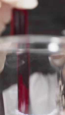 woman scientist with magnifier glass shakes test tube with red liquid in laboratory slow motion. probe lens footage of medical researching macro view
