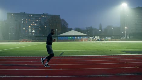 athlete running on track at night stadium