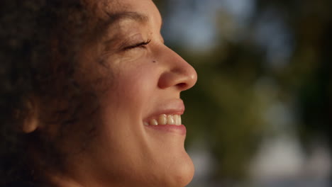 happy african american woman enjoying warm golden sunlight outdoors portrait.