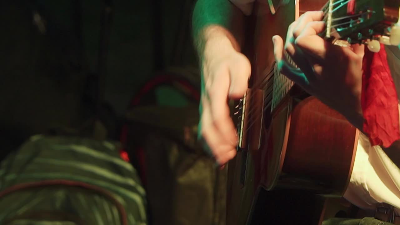 Close-up of a guitar player strumming a "chacarera" on a nylon-string guitar