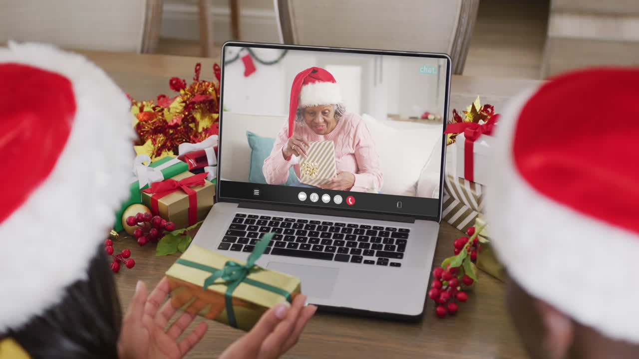animación de una pareja diversa con sombreros de santa en una llamada de video portátil con una mujer en navidad