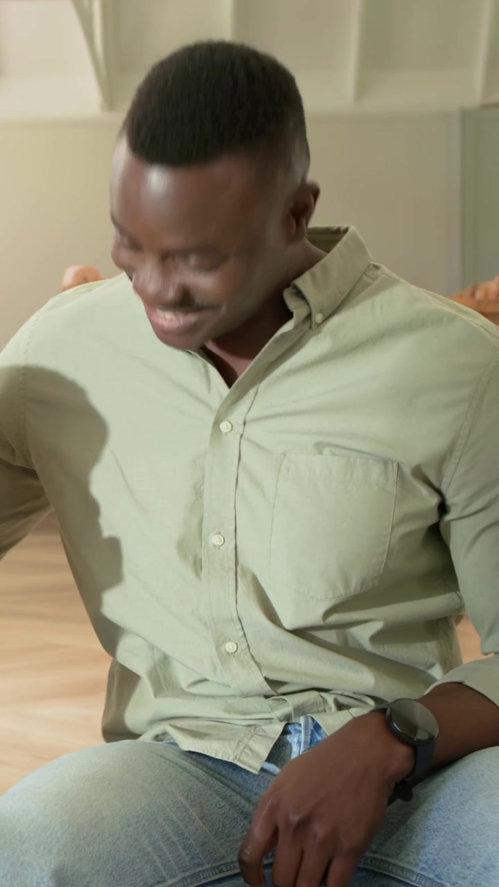 Vertical video: Looking at lap dad in green shirt jeans cheering at home, child hugging, watch seen