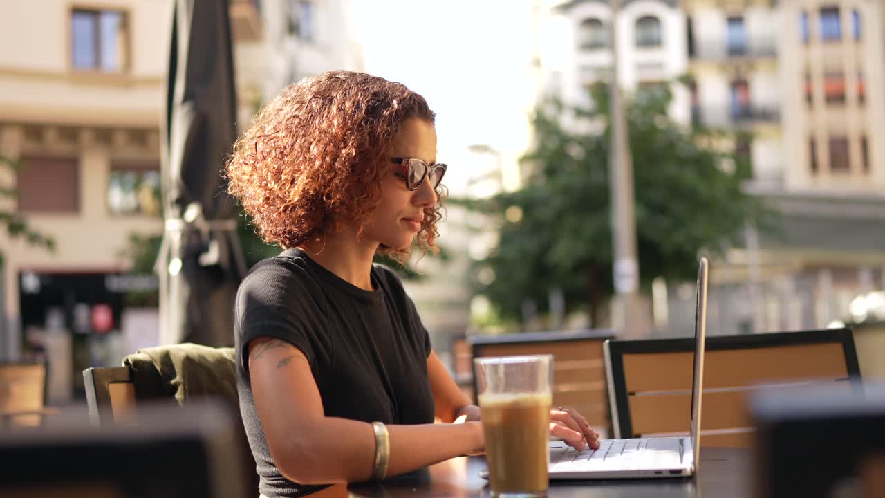 Woman working on laptop at outdoor cafe