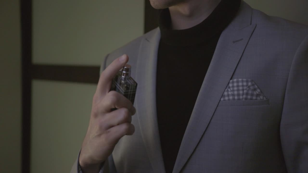 Un uomo che si spruzza il profumo sui vestiti per un evento - inquadratura media