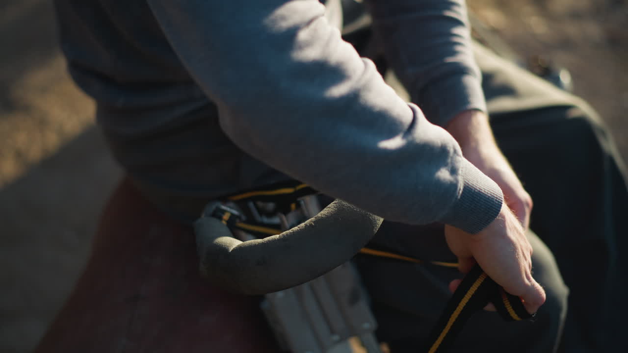 은 재과 어두운 바지를 입고 은 자연 배경으로 야외에서 을 조정하는 손의 클로즈업. 카메라 각은 약간 낮으며 손과 에 초점을 맞추고, 얼굴은 보이지 않습니다.