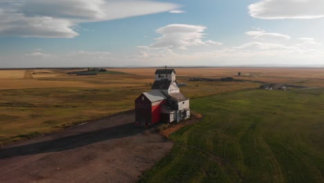tomada aérea de un dron del viejo histórico ascensor de grano de alberta rodeado de campos agrícolas en todos los lados de la ciudad de raleigh, sur de alberta, canadá