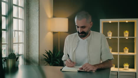 Good-looking motivated Caucasian biographer or novelist author handwrites a biography, romance, or novel in a small notebook
