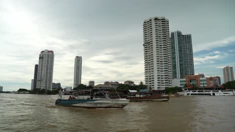 rudimentary boats sailing with riverfront bangkok thai skyline at cloudy day