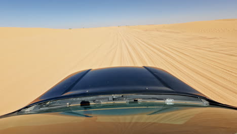 Car-driving-through-the-vast-sandy-dunes-of-the-Sahara-Desert-under-a-clear-blue-sky