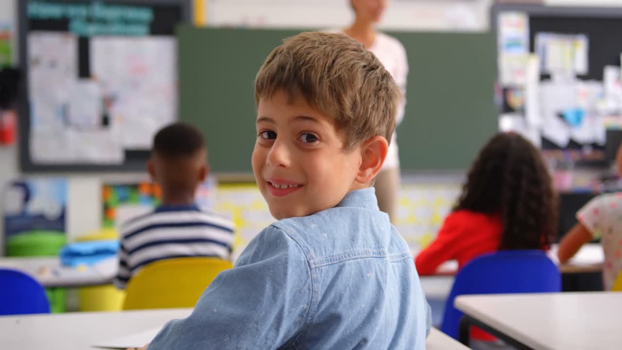 vista trasera de un escolar caucásico feliz mirando a la cámara en el aula 4k