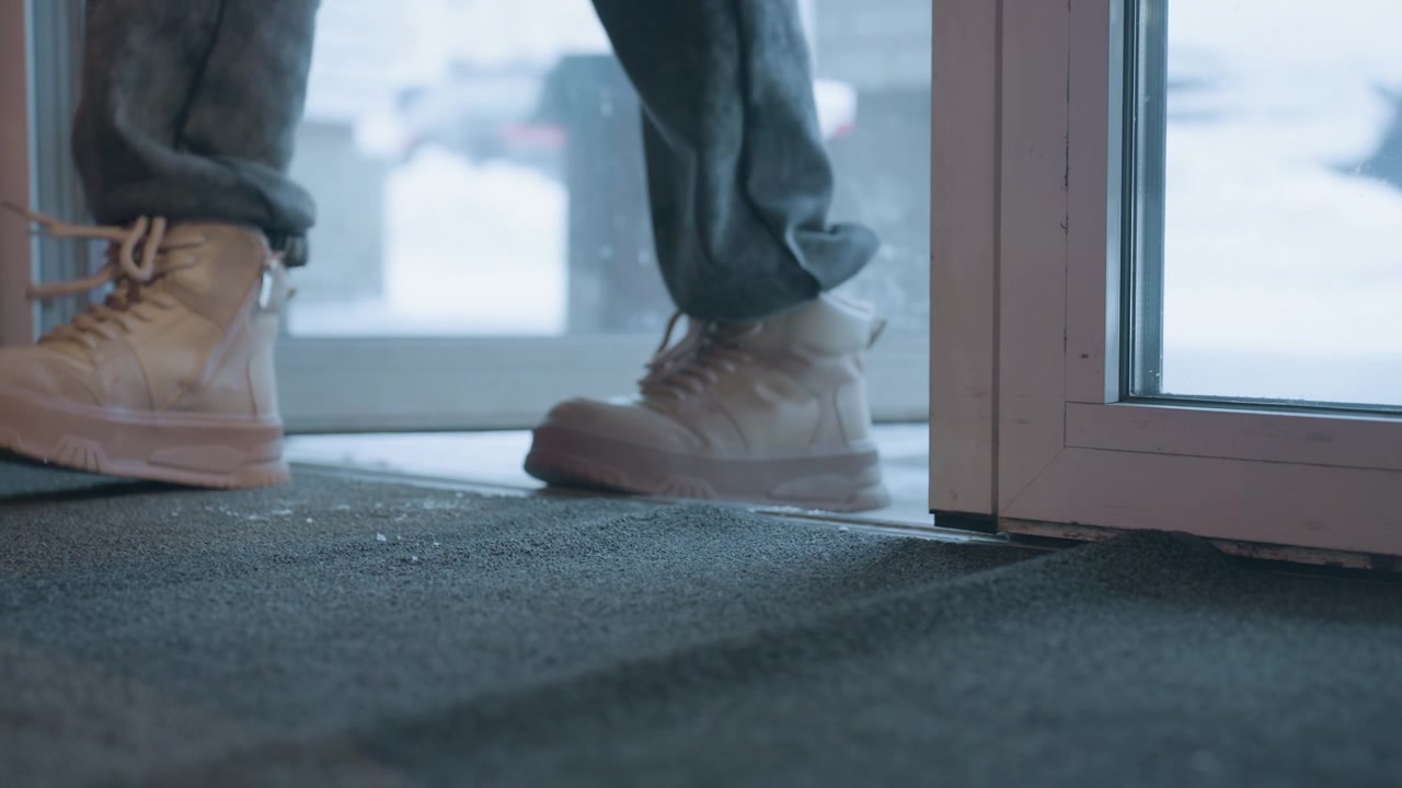 Person in Boots Entering Building from Snowy Outdoors
