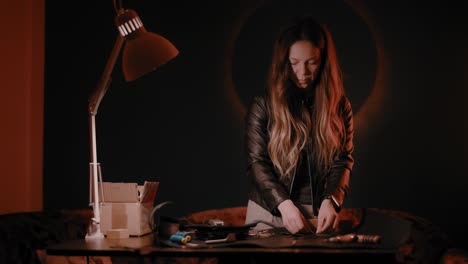 Woman-working-in-a-leather-workshop,-dark-setup,-high-contrast,-color-graded