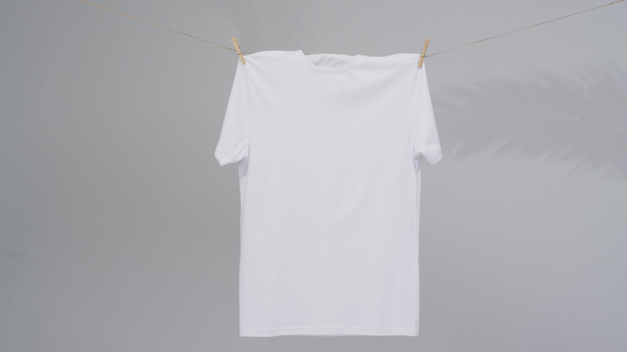 Video of white t shirt with clothes pegs and copy space on grey background